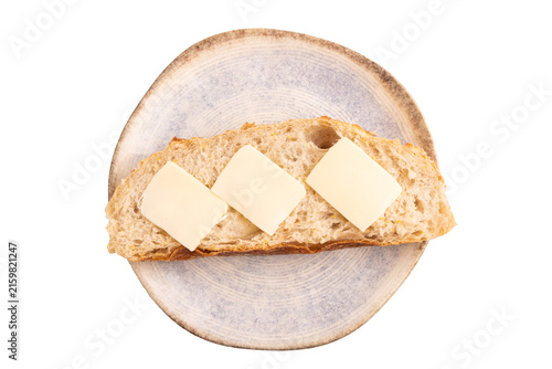 Slice of homemade bread with butter on blue plate isolated on white, close up, top view.