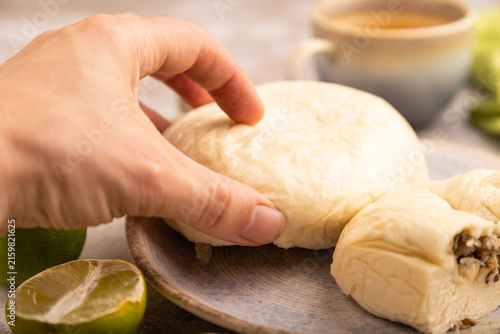 Vietnamese steamed buns Banh bao with hand on brown concrete. side view, close up, selective focus
