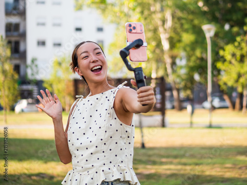 Modern mobile videography concept featuring a cheerful woman creating stabilized selfie footage with a smartphone stabilizer.