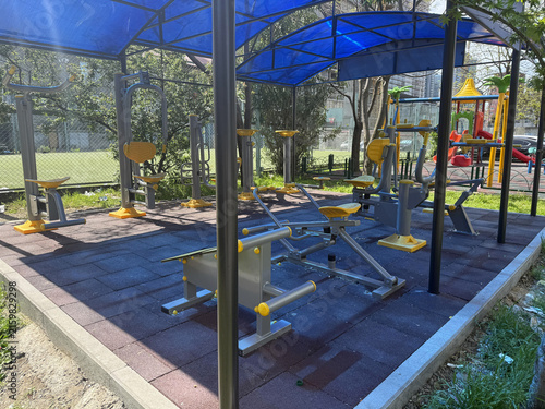 Four pieces of outdoor gym equipment stand in a park