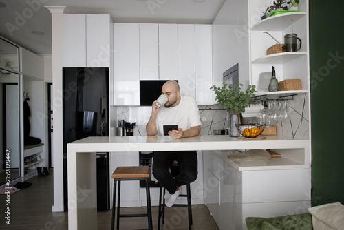 Happy Man Drinking Coffee and Reading Electronic book at Home Lifestyle Portrait
