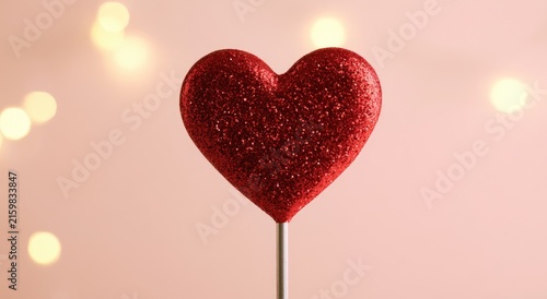 Glittering red heart on a stick with soft bokeh lights in background