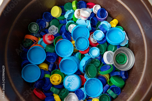 Un grand nombre de bouchons et de couvercles en plastique multicolores (bleus, verts, jaunes, rouges, blancs) rassemblés en vrac, destinés au recyclage ou à des collectes solidaires associatives.