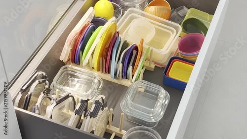 Colorful kitchen drawer filled with organized containers, lids, and utensils