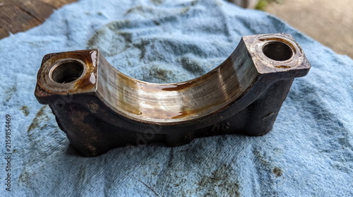 Used oily engine main bearing cap resting on a blue mechanic shop towel