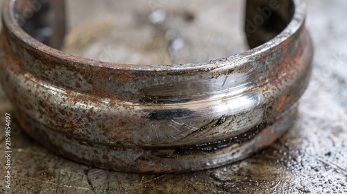 Used rusty metal cv joint retaining clip with wear marks on a greasy surface