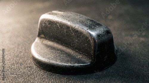 Worn black plastic automotive interior rotary control knob with scratches resting on a dark surface
