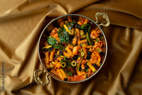 Delicious pasta dish garnished with fresh greens and olives sits elegantly in a beautifully styled bowl