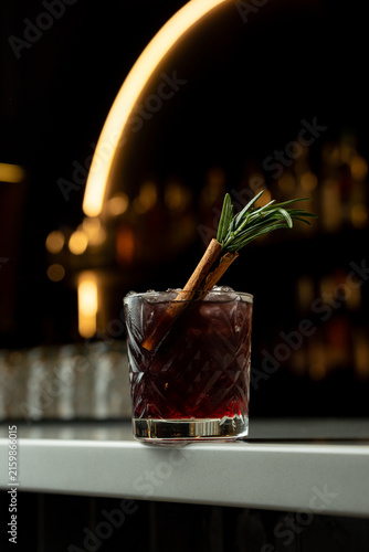 Cuadro en lienzo Sipping a delightful cocktail garnished with rosemary and cinnamon in a cozy, di