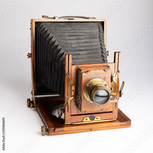 Vintage plate camera made of wood and brass with bellows, shot on a plain white background