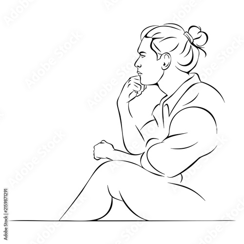 Pensive man with man bun hairstyle sitting and resting chin on hand for psychological reflection mental health awareness or creative brainstorming.