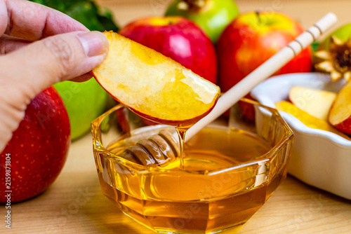 Hand dipping apple slice in honey for rosh hashanah