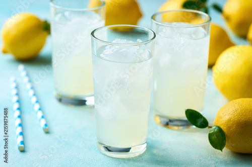 Glasses of freshly made lemonade on turquoise background, selective focus.