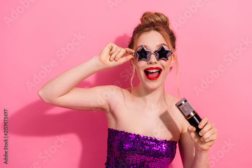 Obraz na płótnie Cheerful cheerful woman in star-shaped sunglass singing into a microphone, weari