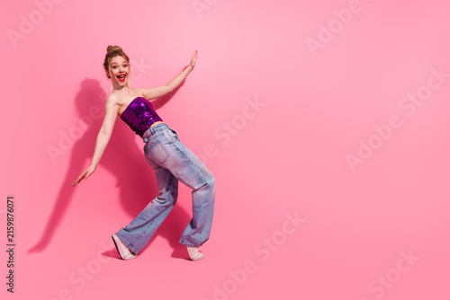 Obraz na plátně Fashionable woman posing in a vibrant outfit against a pink background, expressi