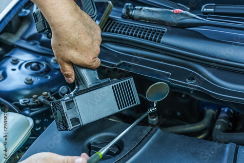 Obraz na płótnie Automotive expert inspecting car engine VIN number with ultraviolet light and mi