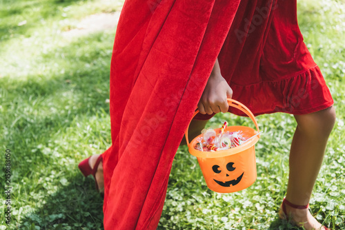 Exciting trick or treating adventure on a spooky Halloween day, kid with bucket of candies 