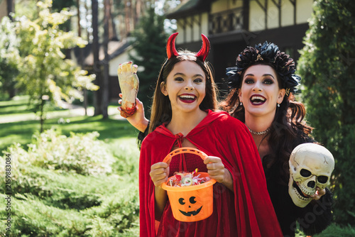 Bild auf Leinwand Mother and child share joyful moments in festive Halloween costumes outdoors