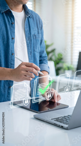 Man using stylus on digital tablet to execute electronic document signatures with holographic security shields for secure data workflow and paperless office business operations.