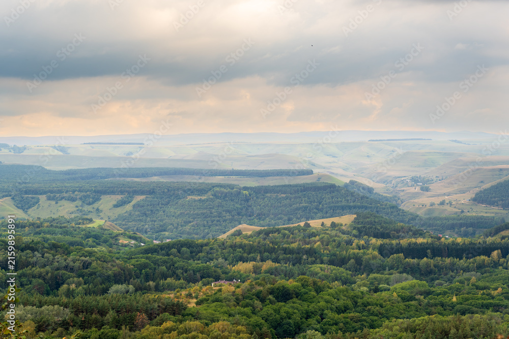 Fototapeta premium Layers of green mountains and hills in the haze during sunset. Panoramic View of Green hills and Meadow.