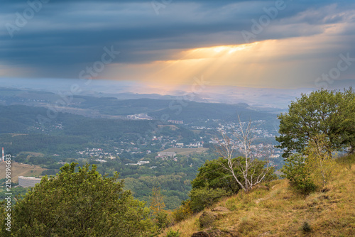 Принти на полотні A mountain range covered in the wild woods illuminated by the golden light of the setting sun