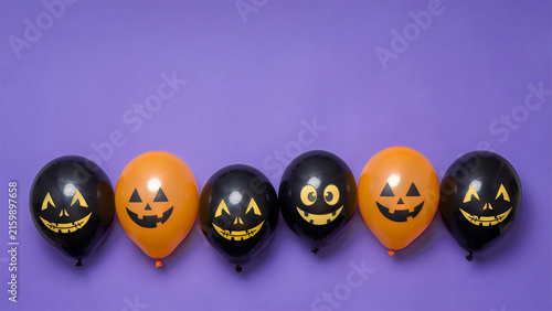 Halloween balloons with spooky jack-o-lantern faces on a purple background