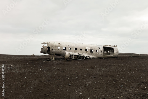 An abandoned crashed airplane fuselage on a black sand desert