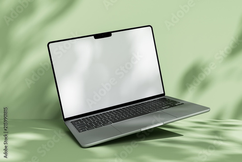 Open laptop mockup with blank white screen on green background with leaf shadow overlay.