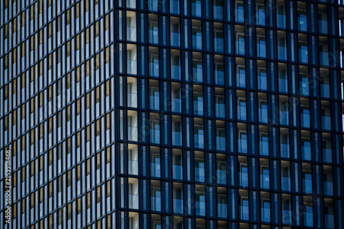 Close-up of a contemporary glass building facade with repeating windows and strong geometric lines, ideal for architecture, corporate, technology, and urban design backgrounds.