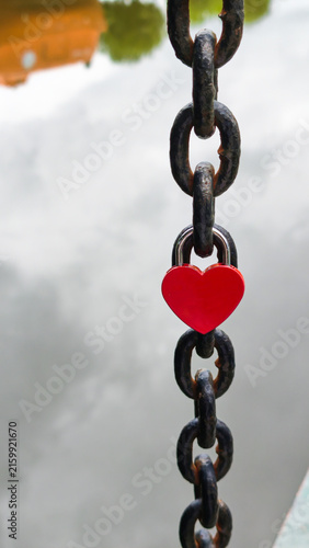 Photography Red heart-shaped love lock on a metal chain in close-up