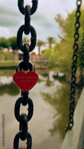 Принти на полотні Red heart-shaped love lock on a metal chain in close-up
