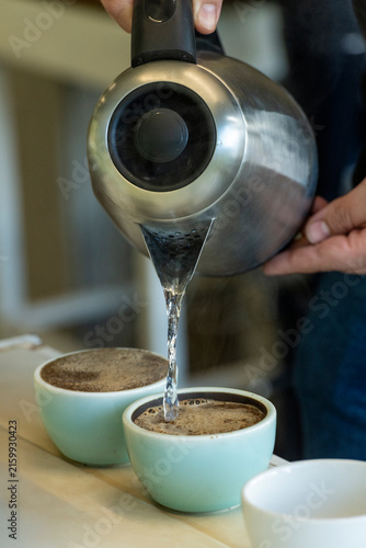 Photography Barista preparing for coffee cupping, pouring hot water from a gooseneck kettle