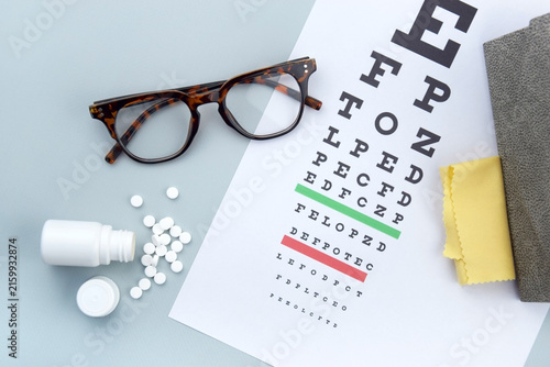 Eye test chart and glasses on blue background