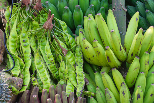 Принти на полотні Bunches of fresh green petai pods (stink beans) and unripe green bananas display
