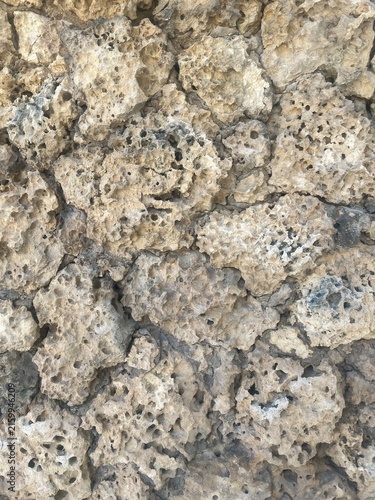 Foto Close-up of a rough porous stone wall with irregular natural rock formations in beige and gray tones