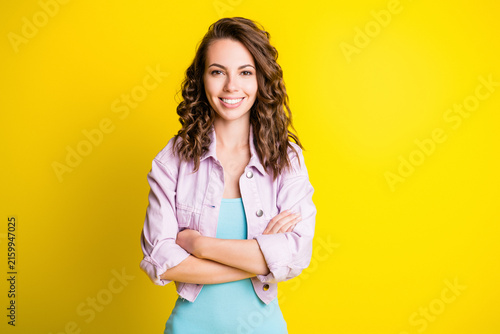 Canvas Print Smiling confident young woman with crossed arms standing against a bright yellow