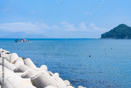 Small Fishing Boat Cruising Open Blue Bay Past Coastal Tetrapod Barrier