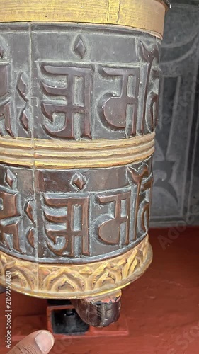 Vertical footage of a traditional Buddhist prayer wheel decorated with the sacred Om Mani Padme Hum mantra and ornamental Buddhist artwork. The close-up captures the detailed religious craftsmanship