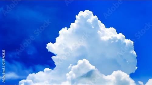 Fluffy white cumulus clouds drift and evolve against a vibrant deep blue sky.