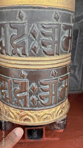 Vertical footage of a traditional Buddhist prayer wheel decorated with the sacred Om Mani Padme Hum mantra and ornamental Buddhist artwork. The close-up captures the detailed religious craftsmanship