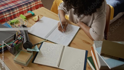 African American teenage boy writing math equations in notebook during study session, high angle view. Video is perfect for online learning platforms and school supply marketing campaigns