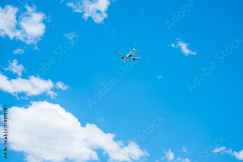 Konstfotografi An airplane flies through a clear blue sky with fluffy white clouds