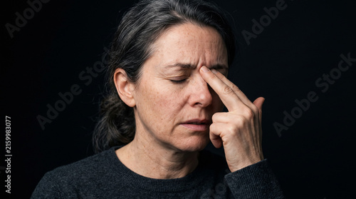 Retrato comercial de alta resolución enfocado estrechamente en un adulto experimentando dolor de cabeza sinusal, presionando suavemente los puntos de presión faciales