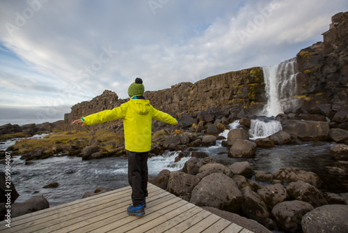 Cute child, boy, enjoying a sunny day in Oxararfoss Waterfall in Thingvellir National Park rift valley, Iceland autumntime