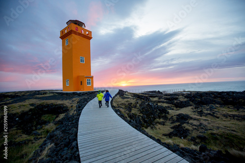 Children running on a path to lighthouse in lava field in beautiful nature in Snaefellsjokull National Park in Iceland, autumntime