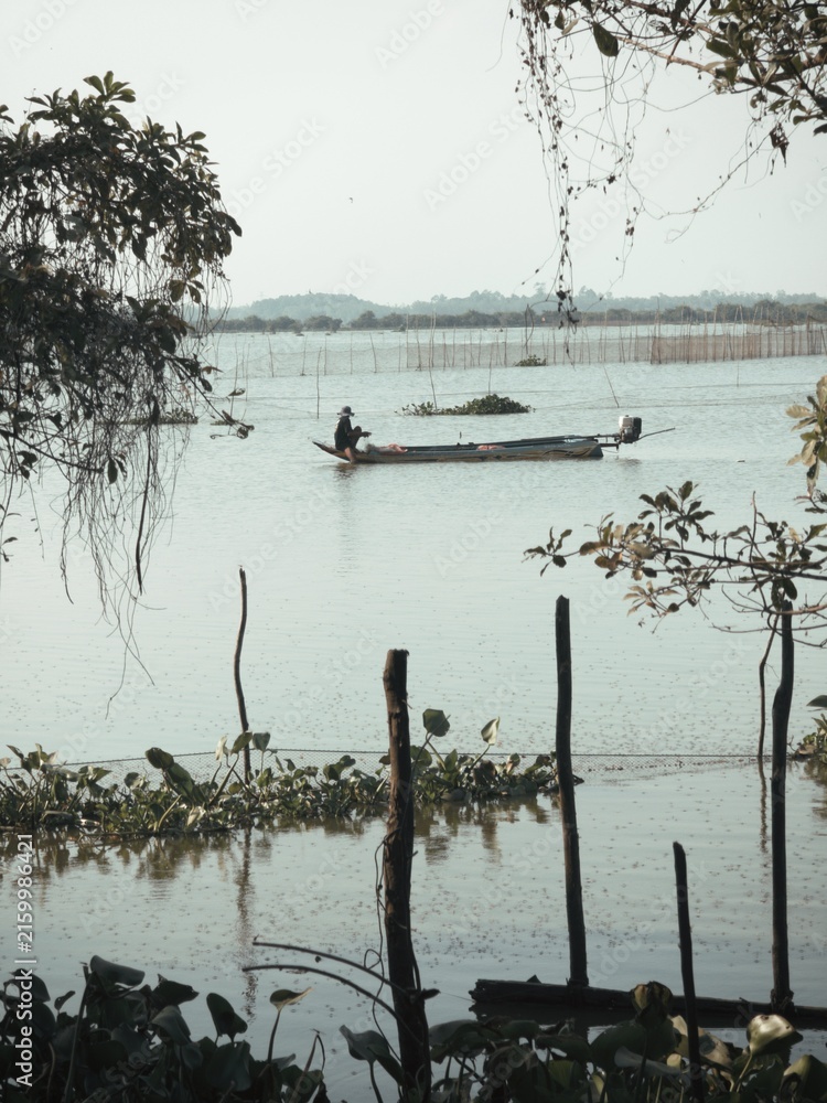 Fototapeta premium Cambodian fisher on long tranditional fishing boat near tonle sap lake Siem Reap Cambodia