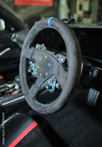 Fotografie A Custom motorsport steering wheel with suede trim and exposed controls inside a modified performance car