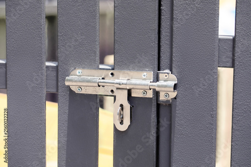 Konstfotografi Close-up of metal gate latch and lock mechanism on gray fence panel, security ha
