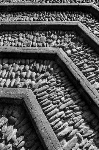 Old cobblestone pavement texture of natural river stones  with geometric concrete borders in black and white. Vertical photography