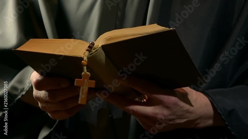 Monk reads from open prayer book and gestures during devotion